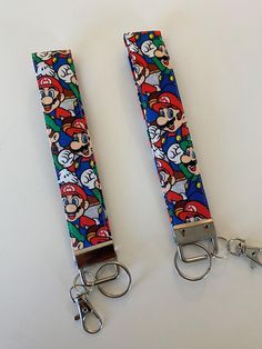 two keychains with mario and luigi on them sitting next to each other in front of a white background