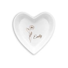 a white heart shaped dish with the word family written on it and a single flower