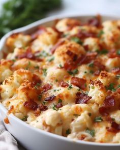 a casserole dish with bacon, cheese and parsley in it on a table