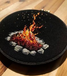 a black fire pit sitting on top of a wooden table