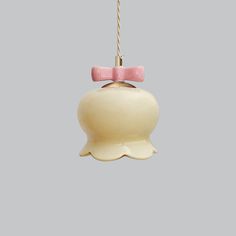 a pink and white bell ornament hanging from a cord on a gray background