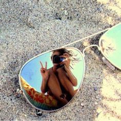 the reflection of a woman in sunglasses on the sand