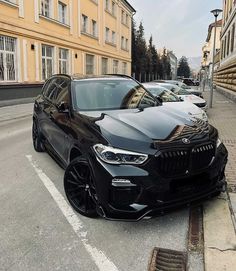 a black bmw suv parked in front of a building