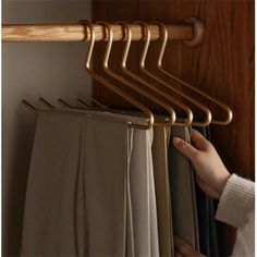 the person is trying to hang their clothes from the rail on the coat rack in the closet