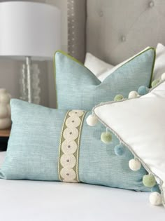 two pillows with pom - poms on them sitting on a bed