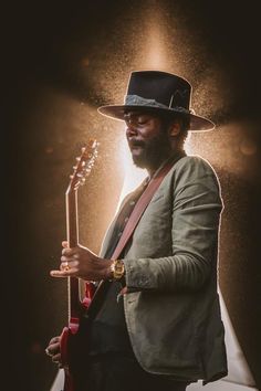 a man wearing a hat and holding a guitar