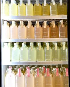 many bottles of liquid are lined up in a refrigerator with labels on the front and sides