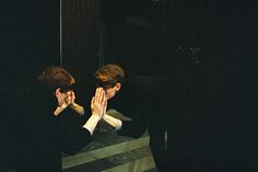 two people standing in front of a mirror with their hands together