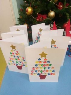 five cards with different designs on them sitting next to a christmas tree