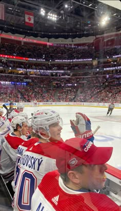 hockey players sitting on the bench in front of an audience at a sporting event,