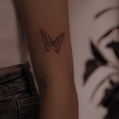 a woman's arm with a small butterfly tattoo on the left side of her arm