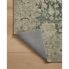 an area rug on the floor with a gray and green color scheme, which has been placed