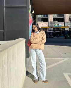 a woman leaning against a wall with her arms crossed