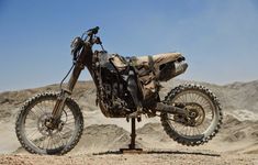 a dirt bike parked on top of a metal stand in the middle of some desert