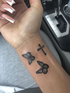 a woman's arm with three butterflies and a cross tattooed on the left wrist