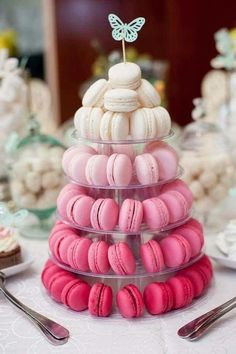 a stack of pink and white macaroons sitting on top of a table next to silverware