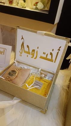 an open box with some items in it on a white tablecloth and gold lettering