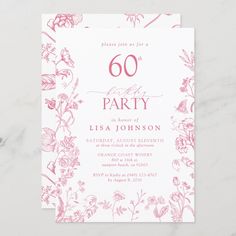 the pink floral 60th birthday party card is displayed on a marble surface with white and red ink