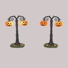 two black and orange street lights with jack - o'- lanterns on them