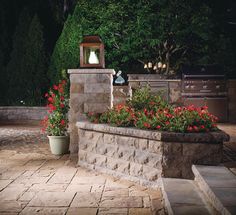 an outdoor area with flowers and a grill in the background at night, surrounded by trees