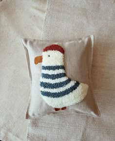 a small stuffed bird sitting on top of a pillow