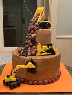 a chocolate cake with construction trucks and grapes on top