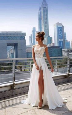 a woman in a white dress standing on top of a roof with her legs crossed