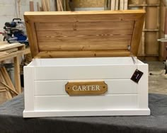 a white wooden box with a name on the lid sitting on a table in a workshop