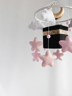 a black box with pink and gold stars hanging from it's sides next to a crescent