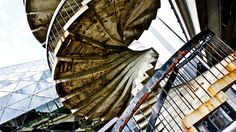 an old spiral stair case in front of a building with glass and steel windows on the side