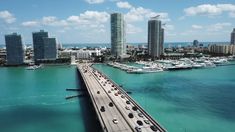 an aerial view of a bridge over the ocean with boats in the water and high rise buildings