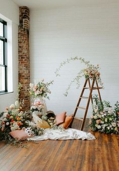 an arrangement of flowers and greenery on the floor in front of a brick wall