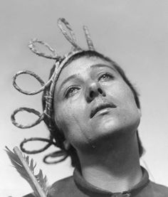 a woman with scissors on her head looking up at the sky and holding a feather