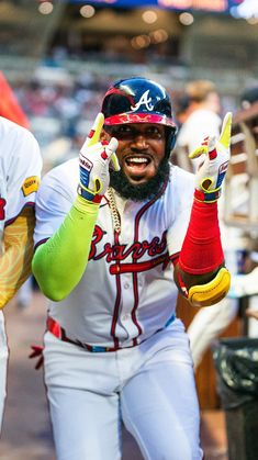 a baseball player with his hands in the air while wearing gloves and holding two fingers up