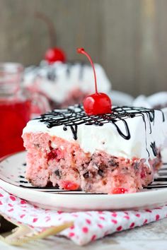 a piece of cake with white frosting and cherries on top sitting on a plate