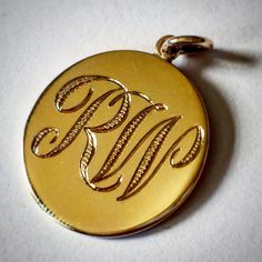 a gold monogrammed pocket watch on a white surface