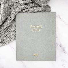 the story of you book sitting on top of a white marble table next to a gray blanket