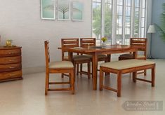 a dining table with four chairs and a bench in front of a wall mounted window