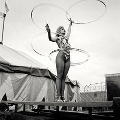 a woman hula hooping on top of a wooden platform