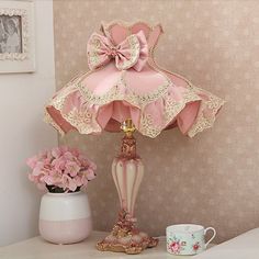 a pink lamp sitting on top of a table next to a cup and saucer