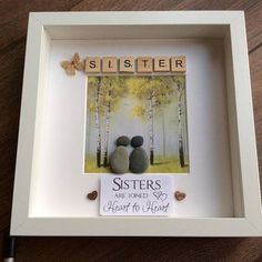 a white frame with two rocks in it and the word sister spelled by scrabbles