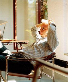 an older man sitting in a chair with his hand on his head