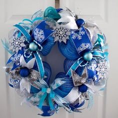 a blue and white christmas wreath hanging on a door