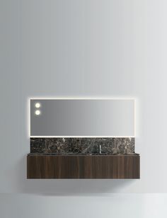 a bathroom mirror mounted on the side of a wall above a counter top with lights