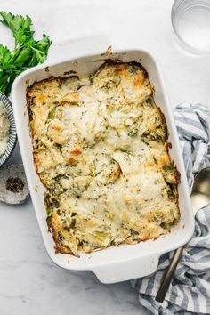 a casserole dish with spinach and cheese in it on a white table