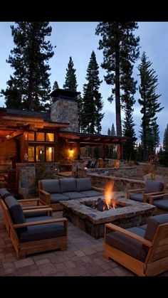 a fire pit sitting in front of a house next to two chairs and a table