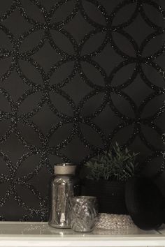 black wallpaper with silver circles on it and vases next to it in front of the mirror