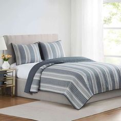 a bed with blue and white striped bedspread in a bedroom next to a window