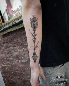 a man's arm with an arrow and cross tattoo on the left inner forearm