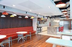 an empty restaurant with red booths and white tables